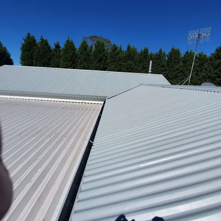 Corrugated residential roof after repainting in a light finish
