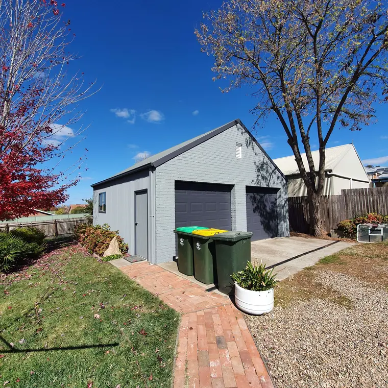 Detached garage after a grey exterior repaint with dark doors