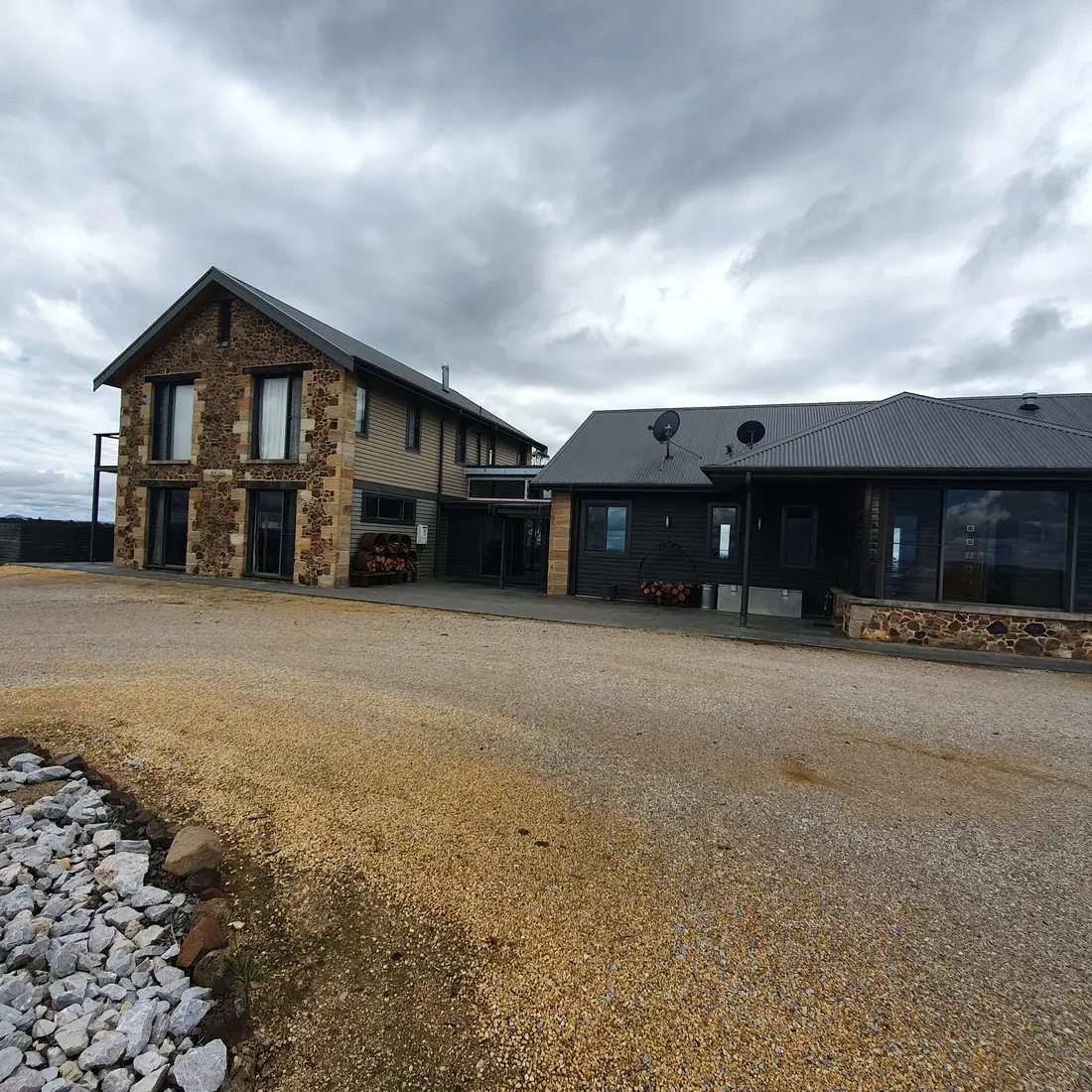 Completed country home exterior with dark cladding and stonework