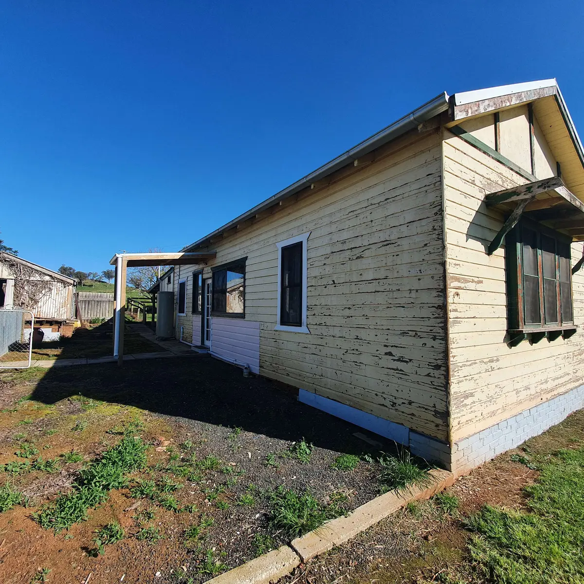 Weatherboard home with worn and peeling paint before restoration
